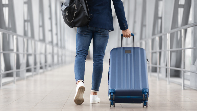 Someone rolling a suitcase through an airport